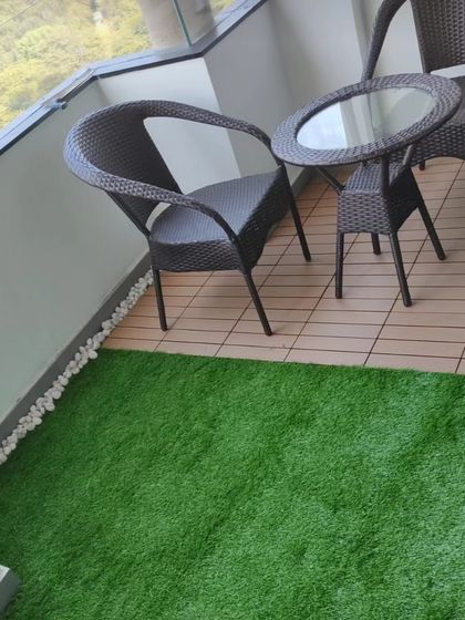 A close up of a balcony corner with both artificial grass and interlocking deck tiles. This combination is easy to clean and provides a solid surface for outdoor furniture.