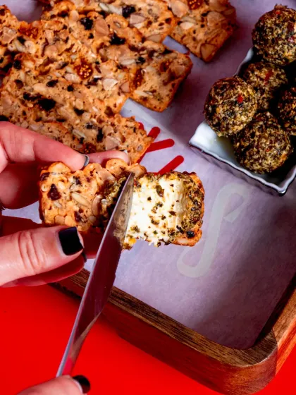A close-up of someone spreading savoury Chèvre Truffle cheese on one of our Fruit 'N' Nut Crisps.