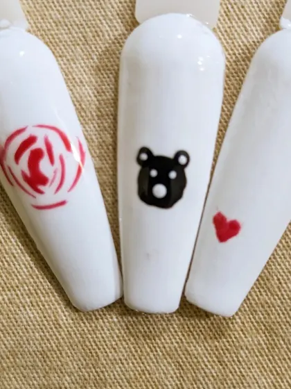 Here are a few cute designs on a clean white base. This shows a simple red rose, a black teddy bear, and a small red heart, perfect for an accent nail.