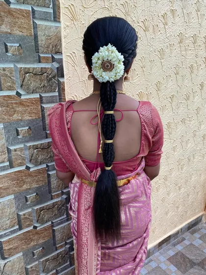 This is a simple yet elegant traditional braid style. The plait is bound in sections with gold thread and topped with a beautiful jasmine flower arrangement, perfect for pre-wedding rituals.
