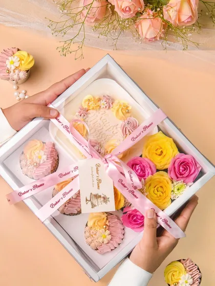A beautifully curated bakery gift hamper, featuring a mini cake and assorted cupcakes, elegantly packaged with a ribbon and fresh flowers. This shot highlights my experience in food product and gifting photography.