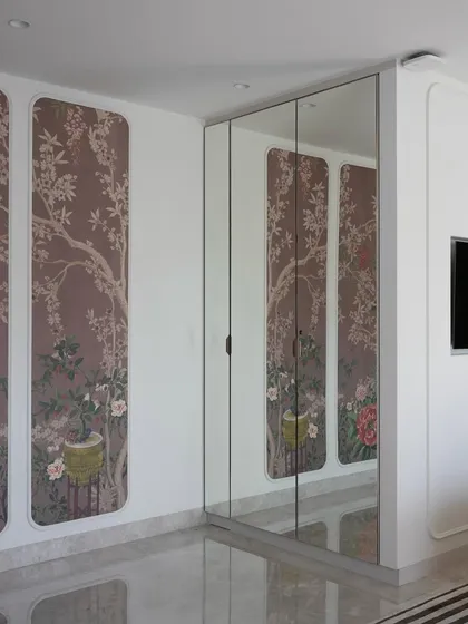 Another view of the parent's bedroom, showing the custom wallpapered wardrobe with mirrored panels. This design choice adds depth and reflects light, making the space feel larger and more elegant.