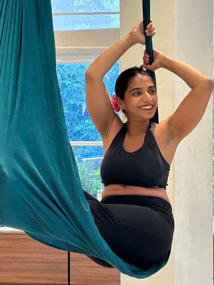 A close-up of a student smiling serenely while resting in the aerial silk. This image captures the pure joy and relaxation that can be found in our classes.