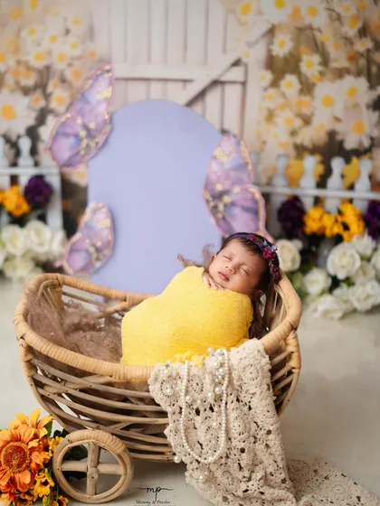 Wrapped snugly in a yellow swaddle, this newborn dreams in a rustic cart. Swaddling helps keep babies calm and content during their session.