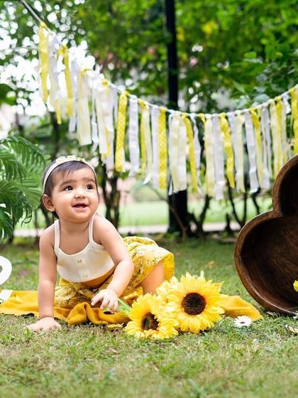 Exploring the garden during her sunflower-themed first birthday shoot. Candid shots like this capture a child's natural curiosity.