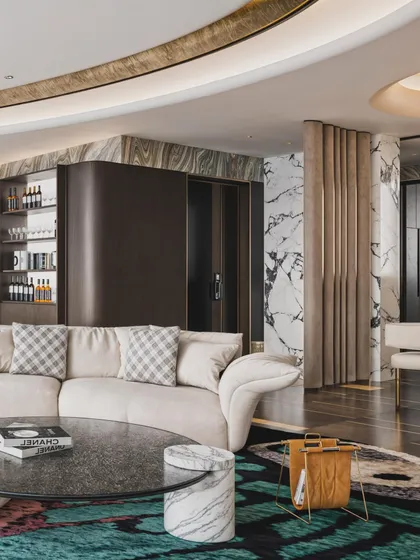 A penthouse living room visualization with a curved sofa and a bold, colorful rug. The render captures the dynamic interplay of shapes and the stunning city view.