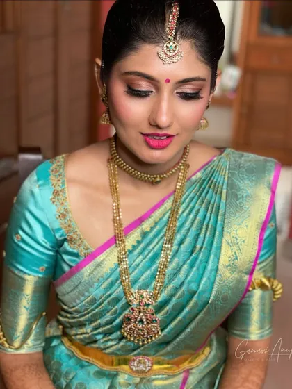 This engagement look for Sushmitha was all about complementing her vibrant turquoise and pink Kanchipuram saree. I used warm, shimmery pink tones on the eyes and a matching lip color to create a cohesive and celebratory look.