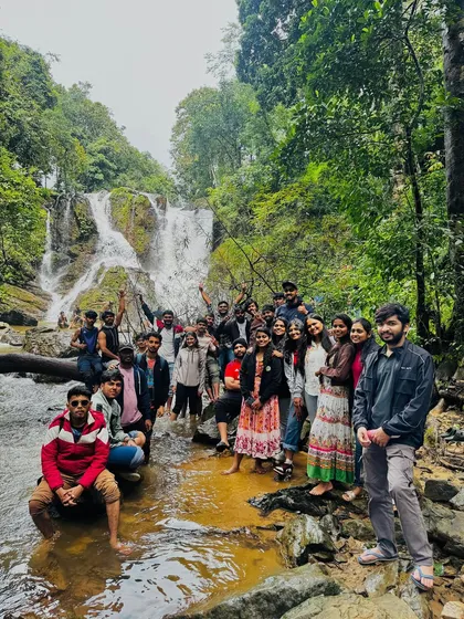A large group from our Independence Day trip posing in front of a beautiful cascading waterfall, a perfect spot for a group memory.