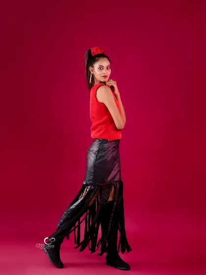 A full-length shot that showcases the unique silhouette of the fringed skirt. The pose is confident and stylish.