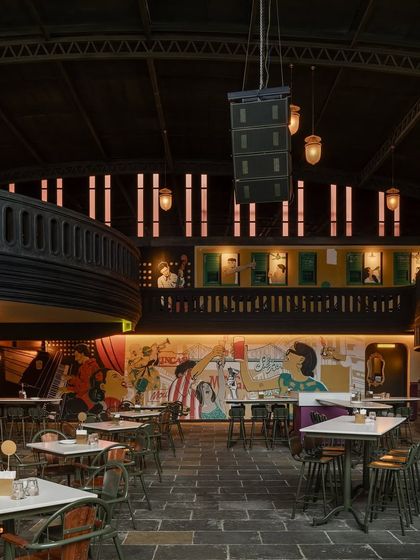 A vibrant mural brings a splash of color and narrative to this seating area. The artwork is a focal point, telling a story that complements the overall Calcutta theme of the bar.