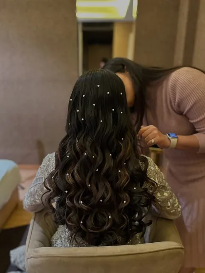 A behind-the-scenes moment, showing the final touches being put on the soft waves with pearls.
