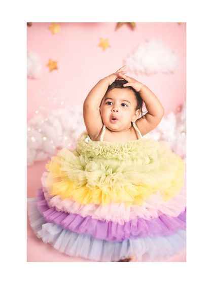 A little girl in a rainbow tutu, looking up with a cute, surprised expression. The pastel colors are so soft and dreamy.