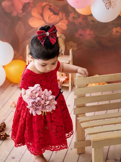 A flower girl in red. This little one looks so sweet and thoughtful, holding a bouquet of pink flowers.