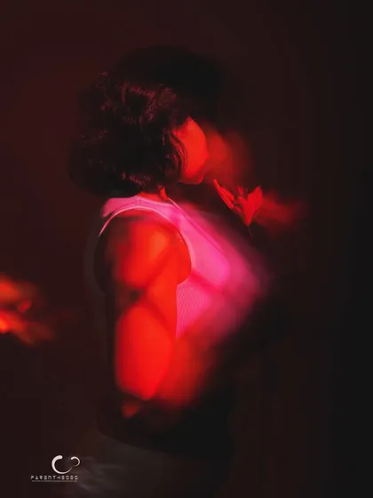 A profile view in a sea of red light and motion. This abstract portrait focuses on silhouette and color to evoke a powerful, emotional response.