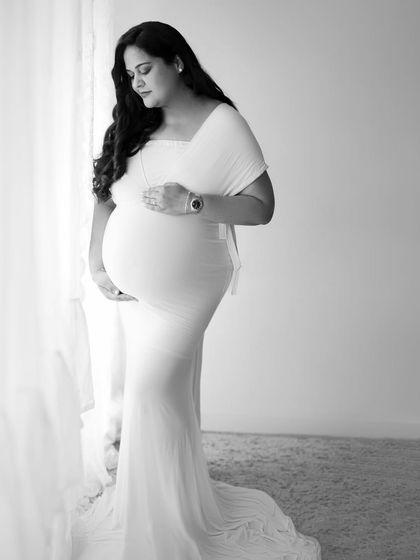 Capturing the grace of motherhood in monochrome. This elegant portrait in a white gown has a soft, ethereal feel in black and white.