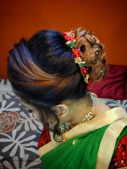A modern and stylish bridal bun with highlights. I created intricate rose-like curls within the bun and added small red flowers for a pop of color.