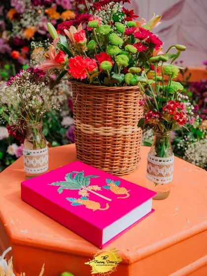 A pop of bright pink from this custom-designed book adds a modern and personal touch to the decor, perfectly complementing the fresh flowers in the background.