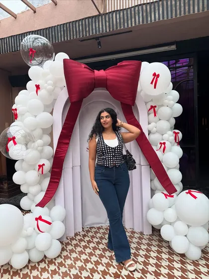 A full-length shot of my casual event look. The flared jeans paired with a patterned waistcoat and a simple white tank is a classic combo that always works. The white sandals keep it fresh and summery.
