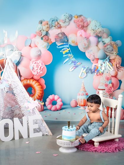 A moment of quiet contemplation before the cake smash begins. This little boy is taking in his beautiful first birthday setup, complete with a blue ombre cake and pastel decorations.