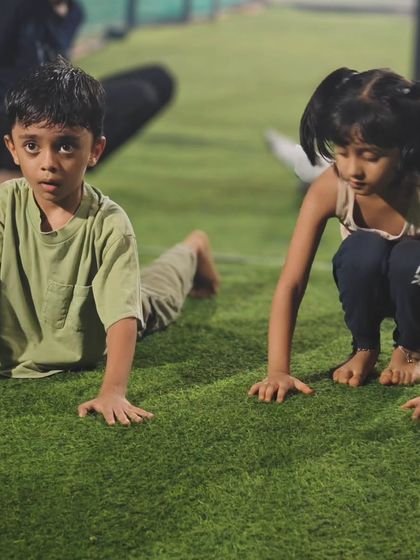 The kids practice the cobra pose together on the turf. This helps build back strength and prepares them for more advanced movements.