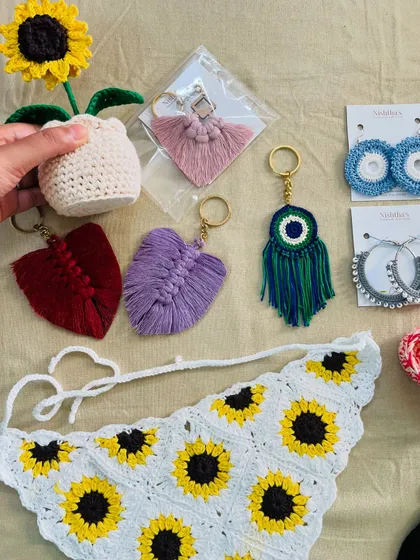 A closer look at some of the custom accessories from a large order. You can see the crochet sunflower pot, leaf-shaped macrame keychains, an evil eye charm, and a sunflower bandana. These small items make for wonderful, personal gifts.