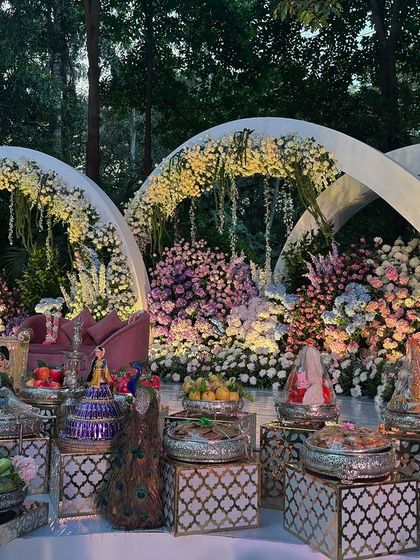 A beautiful evening setup in a garden, with three large floral arches illuminated to create a magical effect.