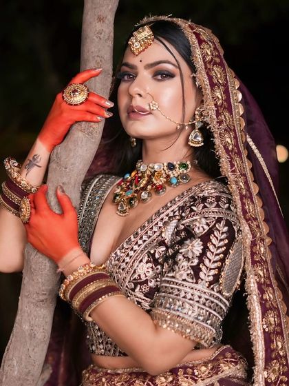 A series of portraits of a bride in a deep wine-colored lehenga. The outdoor, nighttime setting shows the outfit's versatility for reception or sangeet shoots.