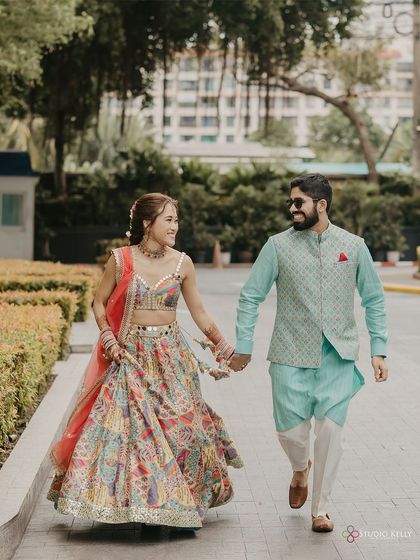 The couple takes a happy stroll outside their Bangkok wedding venue, hand-in-hand, enjoying a moment together.