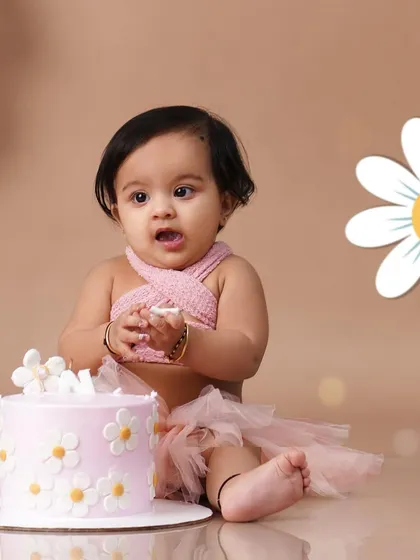 A sweet baby girl in a pink tutu celebrates her first birthday with a daisy-themed cake smash session.