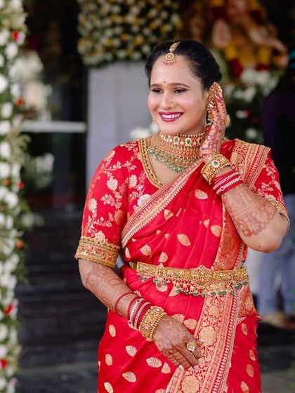 A happy bride in her red Banarasi saree. The rich color and traditional design make this a perfect choice for a wedding celebration.