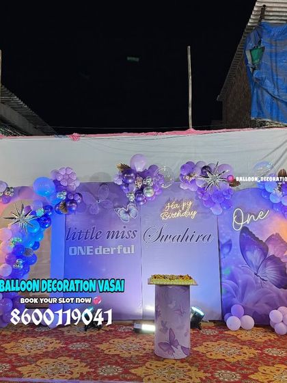 A "Little Miss ONEderful" fairy theme for Swahira's first birthday. This outdoor setup includes a custom purple backdrop, fairy cutouts, and illuminated butterfly wings.