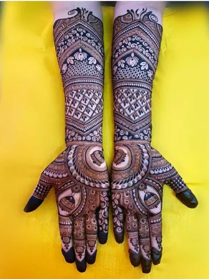 A bold and symmetrical design with large circular mandalas on the palms and intricate floral work on the forearms.