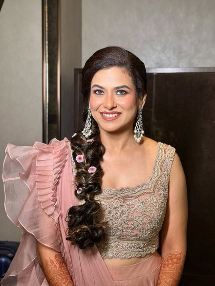 A full-length shot of the bride in her soft pink ruffled saree, looking elegant and modern.