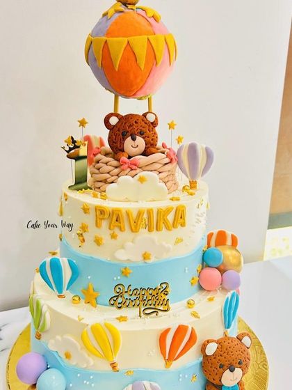 A three-tier hot air balloon cake with adorable teddy bears, perfect for a whimsical birthday adventure.