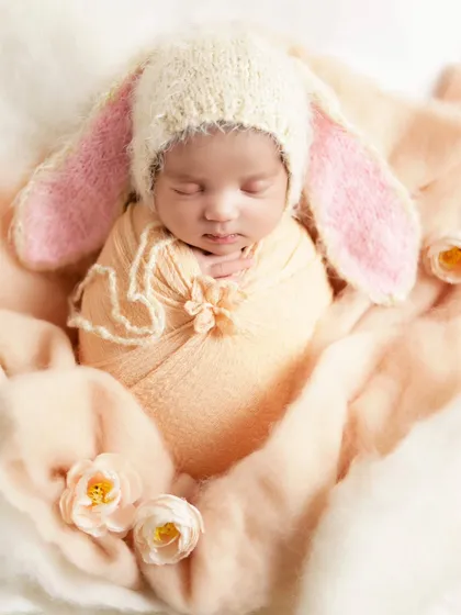 A different angle of the newborn bunny theme, showing the baby nestled among soft fabrics and flowers.