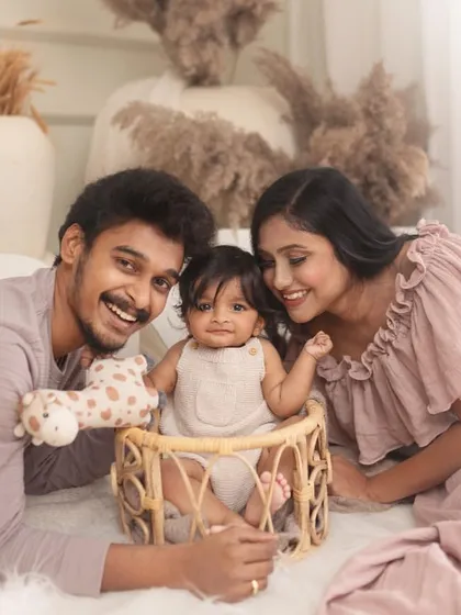 The complete family portrait. Parents surround their happy baby, creating a beautiful image of love and togetherness during this special milestone session.