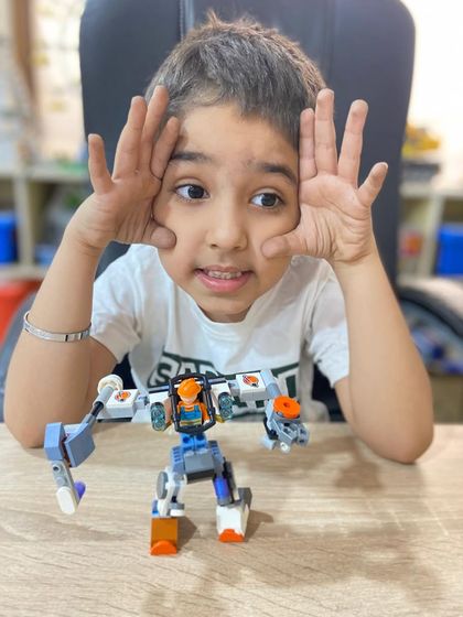 A student shows off her imaginative robot creation, built using a mix of LEGO parts. We encourage free building to spark creativity.