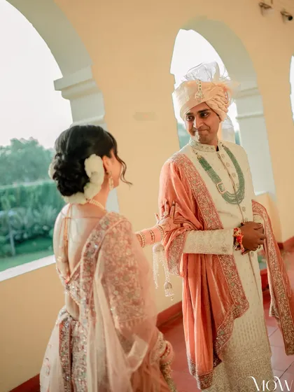 The groom's reaction says it all. A beautiful shot from the first look, showcasing the bride's elegant hair and makeup from the back.
