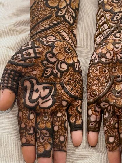 A close up of the palm, showing the name 'Hayat' written in beautiful calligraphy, surrounded by dense Indian-style patterns.
