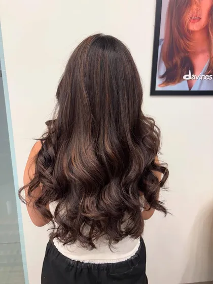 A perfect example of a classic brunette balayage. The soft curls show off the seamless blend of colors and the healthy shine of the hair after styling.
