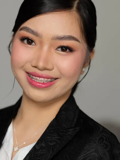 A smiling portrait that shows how the right makeup can boost your confidence. This corporate look is designed to enhance features without being distracting, perfect for the professional world.