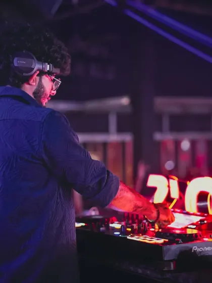 A side view of me working the Pioneer DJ console at Tito's. The club's signature illuminated sign is visible in the background as I line up the next track.