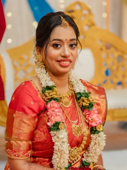 A smiling South Indian bride adorned with jasmine flowers in her hair. The makeup is kept fresh and radiant to match her joyful expression.