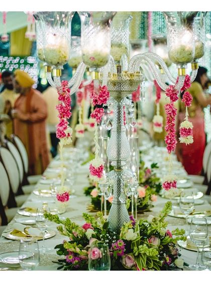 An elegant daytime event setup featuring crystal candelabras adorned with fresh pink flowers, perfect for a sophisticated luncheon or pre-wedding ceremony.