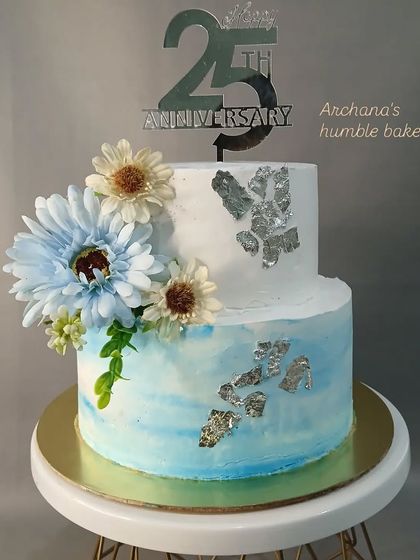A beautiful two-tiered cake for a 25th anniversary. The silver leaf and blue watercolor effect give it a sophisticated and celebratory feel.