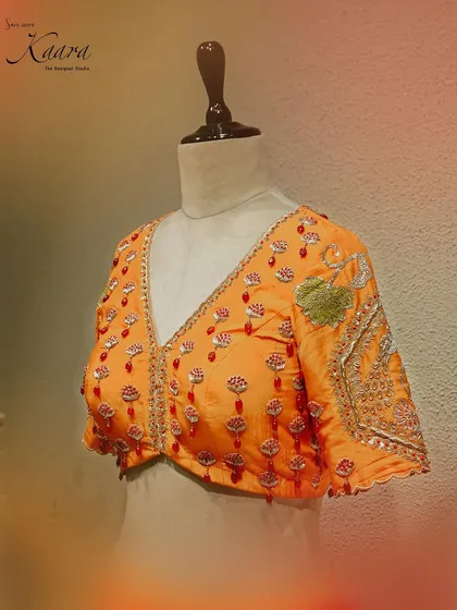 A close-up of the hand-embroidered blouse for our lotus lehenga. The V-neckline is adorned with sparkling red stones and zardosi work, showcasing the detailed craftsmanship that goes into each piece.