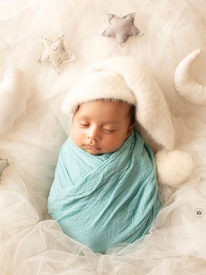 Dreaming on a cloud. This newborn is swaddled in blue and surrounded by soft, felted stars and a moon for a sweet celestial theme.