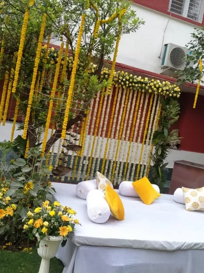 This outdoor setup shows how I use natural elements, like decorating a tree with marigold strings, to blend the decor with the surroundings for a beautiful Haldi function.