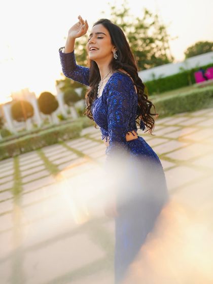 A joyful, candid shot with a lens flare effect, adding a touch of magic to this sparkling blue outfit.