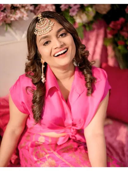 A beautiful close-up of the bride, radiant and happy during her Mehendi. Her bright pink outfit and statement maang tikka complete the festive look.